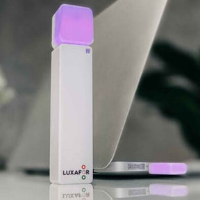 Luxafor Bluetooth Busylight, hvitt på bordet ved datamaskinen lyser lilla